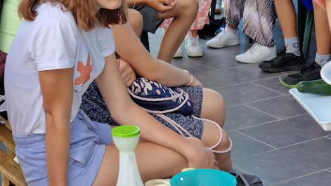 Dzieci siedzą, obok jednej dziewczynki stoi miska z warzywami.